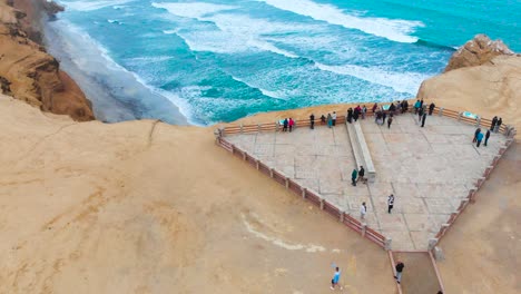 Tilt-up-aerial-shot-as-flying-by-tourists-and-reveal-the-coast-line-of-the-Red-Beach-at-Paracas-National-Park