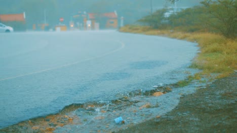 Zeitlupenaufnahme-Von-Regen,-Der-Eine-Ruhige-Straße-In-Curacao-Hinunterströmt,-Während-Der-Verkehr-In-Der-Ferne-Vorbeifährt