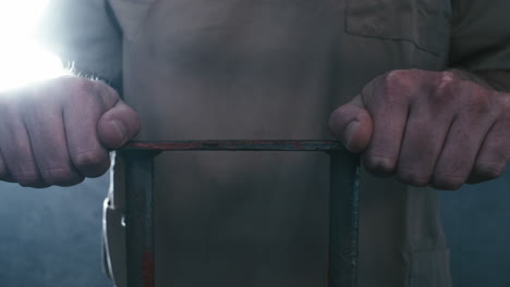 Extreme-close-up-parallax-shot-of-a-prisoner's-hands-holding-onto-the-bars-of-his-cell