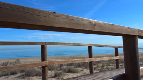 a-Slow-vertical-panning-shot-of-a-wooden-walkway-overlooking-the-blue-ocean-and-white-beach