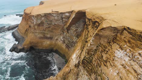Orbital-shot-of-huge-cliffs-at-the-ocean-side,-as-birds-flying-to-their-nesting-place