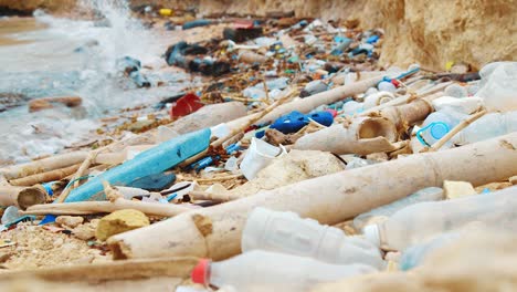 Plastic-bottles-and-rubbish-debris-littered-across-beach,-RACKING-FOCUS
