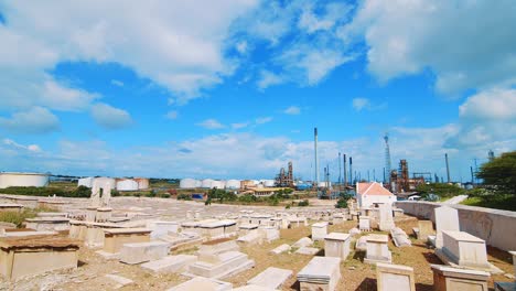 Wide-angle-shot-of-an-empty-cemetery-in-Curacao-with-a-large-industrial-refinery-in-the-background