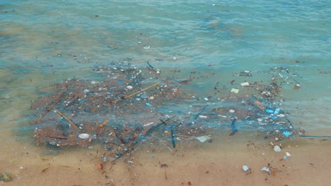 Plastic-pollution-floating-in-Caribbean-Sea-on-tropical-beach,-SLOW-MOTION