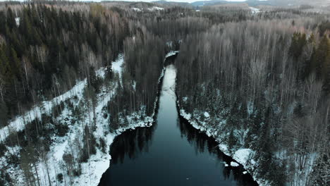 Aerial,-descending,-tilt-down,-drone-shot,-above-a-river,-at-leafless-forest,-first-snow-on-the-ground,-near-Joensuu,-North-Karelia,-Finland