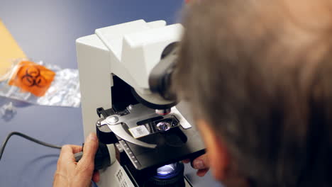 A-scientist-examining-a-slide-with-cancerous-cells-through-a-microscope-in-a-medical-research-laboratory