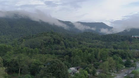 Tiro-De-Drone-Ascendente-De-Montañas-Verdes-Y-Exuberantes-Con-Nubes-En-La-Parte-Superior-Recortada