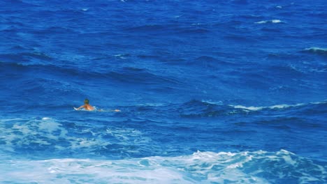 Slow-motion-shot-of-surfers-paddling-out-into-the-surf-at-a-beautiful-sunny-beach-in-Curacao
