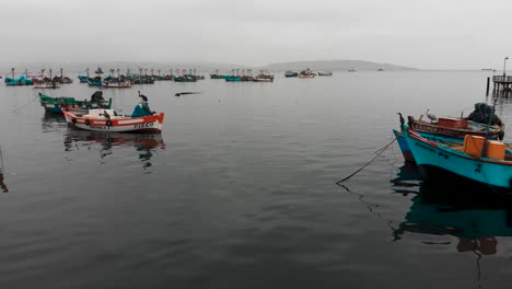 Aerial-shot-as-camera-flies-between-fishing-boats-floating-on-the-ocean,-near-Paracas-town-in-Peru