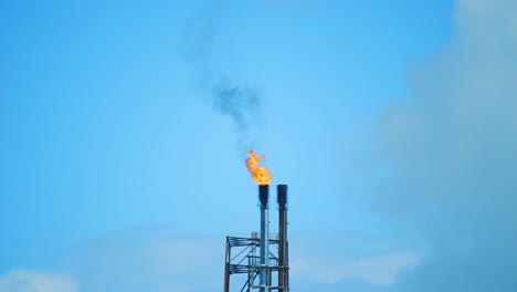 Industrielles-Raffinerierohr,-Das-Feuer-Und-Schwarzen-Rauch-In-Einen-Klaren-Blauen-Himmel-Ausstößt