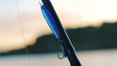 Metal-fishing-lure-attached-to-fishing-rod-with-beautiful-sunset-in-the-background