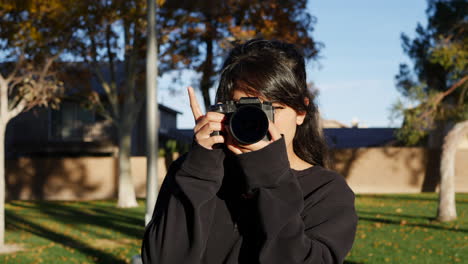 A-hot-girl-photographer-happy-and-smiling-in-autumn-leaves-at-sunset-taking-pictures-with-a-digital-camera-in-slow-motion