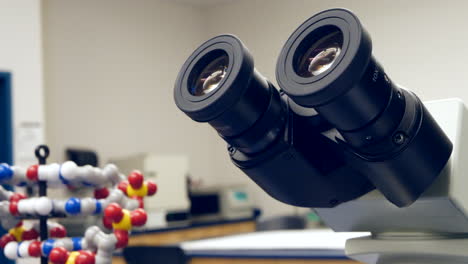 Ein-Student-In-Einem-College-Klassenzimmer-Für-Biologiewissenschaften,-Der-Ein-Experiment-Hinter-Einem-Mikroskop-Und-Einem-Dna-Doppelhelix-Modell-Durchführt