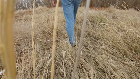 A-legs-walking-through-tall-grass-in-winter-or-autumn---slow-motion