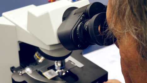 Ein-Wissenschaftler,-Der-In-Einem-Forschungslabor-Für-Medizinische-Biologie-Durch-Die-Linse-Eines-Mikroskops-Auf-Menschliche-Krebszellen-Blickt