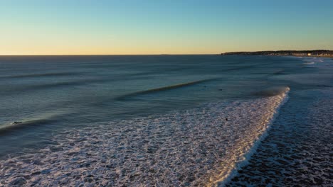 Stationäre-Luftaufnahmen-Von-Wellen,-Die-Auf-Die-Küste-Zusteuern,-Während-4-Surfer-Warten-Und-Eine-Möwe-An-Einem-Kalten-Dezembermorgen-In-York-Beach,-Maine,-Auf-Die-Küste-Zufliegt
