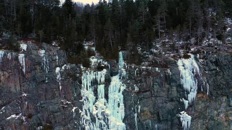 Aerial-ORBIT-around-a-giant-mass-of-icicles-on-a-tall-steep-cliff-in-Maine