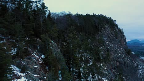 Aerial-footage-flying-close-along-the-ridge-of-a-snowy-mountain-with-a-steep-cliff-face