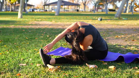 A-woman-stretching-during-a-workout-in-slow-motion-on-a-purple-yoga-mat-in-a-park-at-sunset