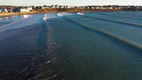 Aerial-footage-following-waves-into-shore-in-York-Beach-Maine-on-a-cold-windy-December-morning-with-beach-houses-in-the-distance