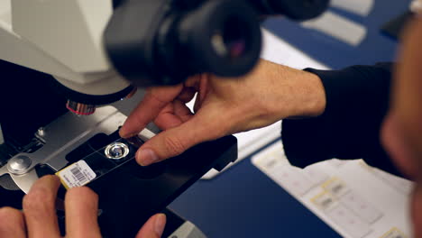 A-scientist-preparing-a-slide-of-his-own-cancer-cells-from-a-medical-biopsy-on-a-microscope-in-a-medical-research-science-lab
