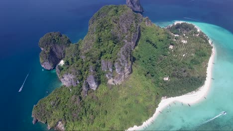 Epic-reversal-drone-shot-over-a-mountainous-tropical-island-surrounded-by-turquoise-and-navy-blue-water