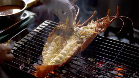 Large-red-lobster-filleted-on-barbecue-grill-being-prepared-with-grated-cheese,-Smoking-over-flames