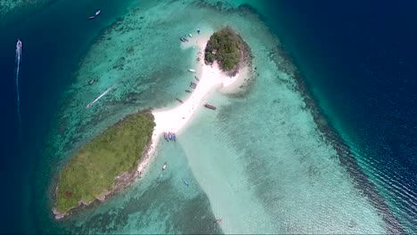Thrilling-aerial-shot-over-a-small-tropical-island-surrounded-by-beautiful-turquoise-water