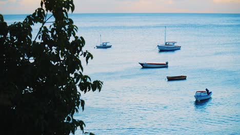 Small-group-of-fishing-boats-bobbing-on-the-calm-water-during-sunset-in-Curacao,-Caribbean