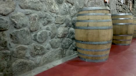 Slow-panning-shot-down-a-winery-hallway-lined-with-wooden-barrels