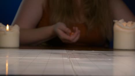 Woman-Rolls-Orange-Twenty-Sided-Die-Across-Game-Table-with-Candles-Lit