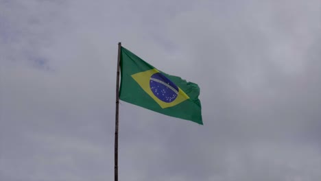 Zeitlupenaufnahme-Der-Brasilianischen-Flagge-Auf-Der-Stange,-Die-An-Bewölkten-Tagen-Im-Wind-Geblasen-Wird