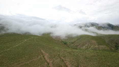 Ascending-aerial-view-above-cloudy-green-mountain-range