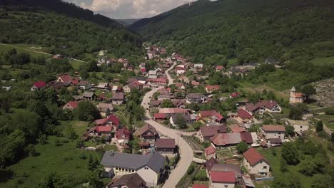Drone-shot-of-a-small-Slovak-village-sorrounded-by-mountains-and-forests,-on-a-sunny-day