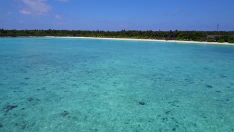 Low-wide-soft-aerial-push-in-close-to-Caribbean-crystal-clear-water-towards-remote-beautiful-tropical-island