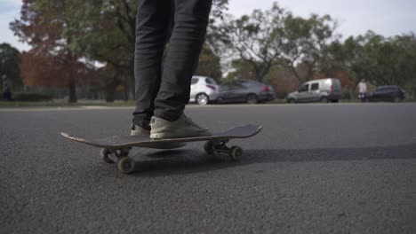Die-Beine-Und-Das-Board-Eines-Skateboarders,-Der-In-Zeitlupe-Auf-Einer-Asphaltierten-Straße-Vorbeifährt