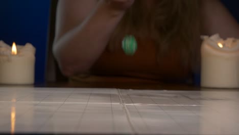 Woman-Rolls-Green-Twenty-Sided-Die-Across-Game-Table-with-Candles-Lit
