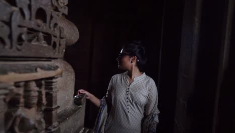 A-Female-Visitor-Looking-At-The-Interior-Wall-Sculptures-While-Walking-Around-Inside-Khajuraho-Temple-In-Madhya-Pradesh,-India