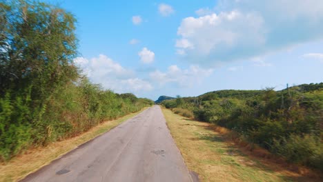 Driving-down-a-rough-and-patched-up-rural-road-in-Curacao,-Caribbean