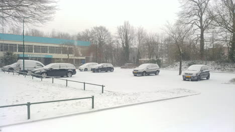 Snow-covered-parking-lot-with-several-cars