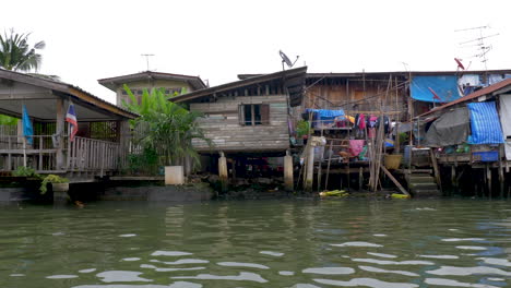 Panning-shot-along-river-route-passing-Asian-waterfront-village-as-seen-from-boat