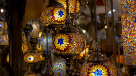 Slow-panning-shot-across-many-glowing-mosaic-glass-patterned-colourful-Moroccan-style-lanterns-hanging-from-ceiling