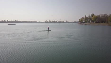 Drone-shot-of-a-person-paddle-boarding-on-a-lake-on-a-sunny-day