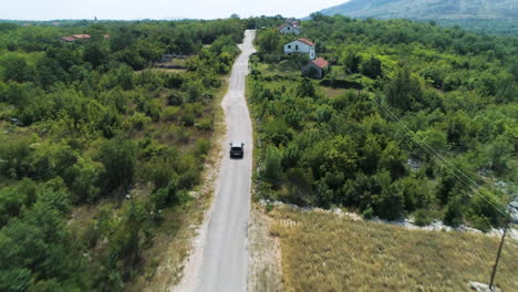 Sobrevuelo-Aéreo-De-Un-Coche-Conduciendo-Por-Una-Carretera-Rural-En-Las-Montañas-Cerca-De-Ljubuski-En-Bosnia-Y-Herzegovina