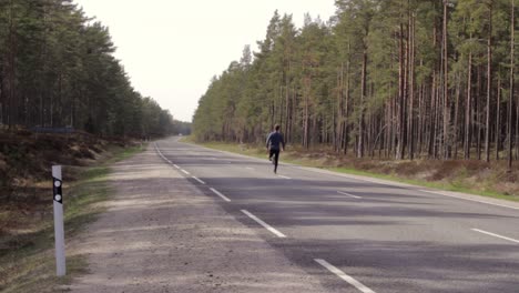 Single-marathon-runner-on-middle-of-road,-wears-blue-black-clothes,-static
