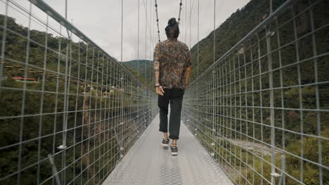 Mann,-Der-Während-Der-Tour-In-Banos-De-Agua-Santa,-Ecuador-über-Eine-Brücke-Geht