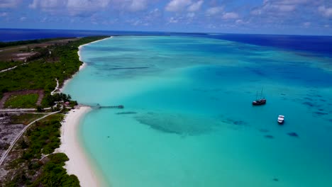 Vista-De-ángulo-Alto-De-La-Laguna-De-Maldivas,-Viejo-Barco-De-Madera-Y-Yate-De-Lujo-Anclado-En-Aguas-Azules