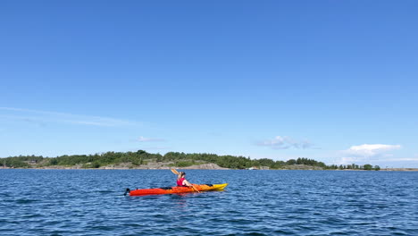Woman-on-a-kayak-paddling-towards-island-in-open-water