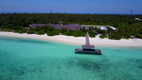 Beautiful-Hanimaadhoo-island-resort-and-jetty,-Maldives-aerial-on-sunny-day