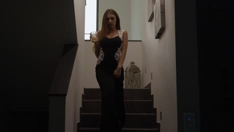 Medium-shot-of-a-wealthy-women-walking-down-the-stairs-in-a-modern-fashionable-house-with-lights-flicking-in-a-dramatic-manner